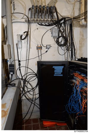 This photograph depicts an electrical installation system featuring circuit breakers, junction boxes, and extensive wiring in what appears to be a basement or utility room. The image shows a wall-mounted electrical panel with multiple breakers at the