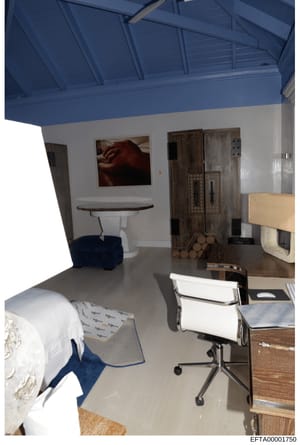 This is a photograph of an interior room, likely from one of Epstein's properties, showing a modern space with a distinctive blue ceiling, white walls, and mixed furnishings including a bed, desk, office chair, round table, and wooden cabinets. The r
