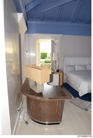This photograph documents an interior bedroom space with contemporary design, featuring a blue vaulted ceiling, modern furnishings, and access to an outdoor patio area with landscaping. The image appears to be architectural documentation or property 