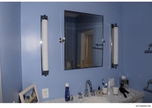 This is a photograph of a bathroom interior, showing a vanity counter with mirror and lighting fixtures. The image appears to be from a property inspection or inventory documentation, likely taken as evidence during the investigation of one of Jeffre