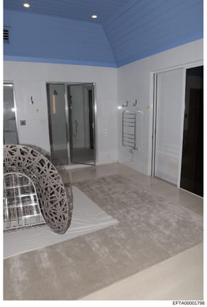 This is a photograph of a contemporary bathroom or spa area featuring white walls, a distinctive blue vaulted ceiling, modern shower enclosure, heated towel rack, and decorative woven spherical furniture. The space appears to be part of a luxury resi