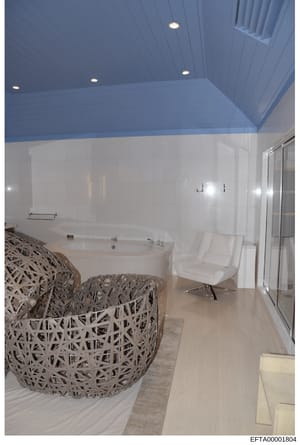 This is a photograph of a high-end bathroom interior featuring a large oval soaking tub, decorative woven seating elements, and modern furnishings. The image appears to be documentation of property interior design or features, likely from one of Epst