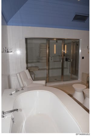This photograph shows a high-end bathroom interior featuring a large freestanding soaking tub, extensive glass-enclosed shower enclosure, and upscale finishes. The image documents the interior design and amenities of what appears to be a residential 