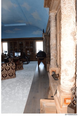 This photograph depicts the interior of an upscale residential property, showing a hallway or corridor with elaborate architectural details including decorative columns with carved capitals, ornate wall paneling, and a blue skylight. In the backgroun