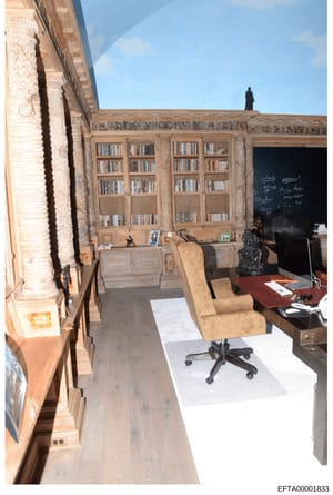 This is an evidence photograph showing an interior office or study space with ornate built-in wooden bookshelves, a desk with office equipment, and furniture. The room features decorative architectural elements and appears to be from a residential pr