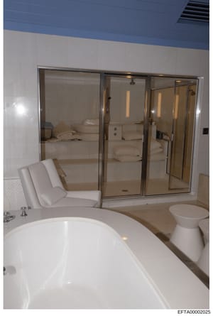 This is a photograph of a luxurious master bathroom featuring a large freestanding soaking tub, walk-in shower enclosure with glass doors, and high-end finishes. The image appears to be from an Epstein property documentation and may be used as eviden