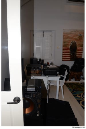 This is an evidence photograph depicting an interior room containing audio and electronic equipment. The room shows a white closet with louvered doors, professional audio equipment including what appears to be mixing boards and amplifiers on a white 