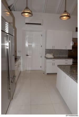 This is a photograph of a modern kitchen interior, showing contemporary design and finishes. The image captures white cabinetry, granite countertops, stainless steel appliances, pendant lighting, and tile flooring. This type of evidence photo would h