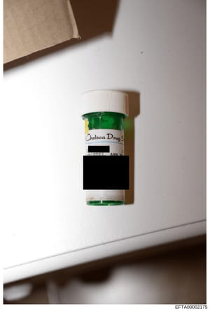 This is an evidence photograph showing a green prescription medication bottle with a white cap and a label reading 'Chelsea Drug Store.' A significant portion of the label is redacted with a black bar, obscuring the patient name, prescription details