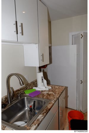 This is a color photograph of a modern kitchen interior showing countertops, cabinetry, sink, and appliances. The image appears to be from a property inspection or inventory documentation related to an Epstein property, as indicated by its Bates numb