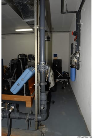 This photograph depicts the interior of a mechanical or utility room, showing HVAC equipment, water filtration systems, and various mechanical components. The image documents what appears to be building infrastructure, potentially from one of Epstein