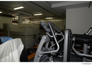 This photograph documents the interior of a fitness facility or gymnasium, showing multiple pieces of exercise equipment including elliptical machines and other cardio equipment. The image appears to be part of the investigative evidence documenting 