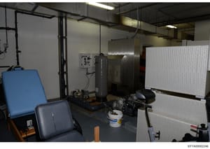 This is an evidence photograph showing an interior room or workspace containing various industrial and laboratory equipment. The space appears to be a utility or technical area with HVAC systems, metal storage units, electrical panels, and miscellane