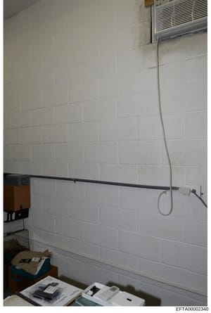 This is an evidence photo from the Epstein investigation showing an interior room with white subway tile walls, electrical wiring, outlets, and what appears to be an air conditioning unit. The image captures basic room infrastructure and appears to b