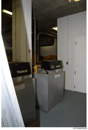 This is an evidence photograph showing the interior of a mechanical room or basement space containing heating, ventilation, and air conditioning (HVAC) equipment branded 'Tramont.' The photo documents industrial-scale climate control systems, likely 
