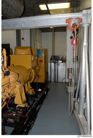 This photograph shows an interior view of a generator room, likely in one of Epstein's properties, containing industrial equipment including a yellow diesel generator, a chain hoist system with red and orange rigging, and various electrical and mecha