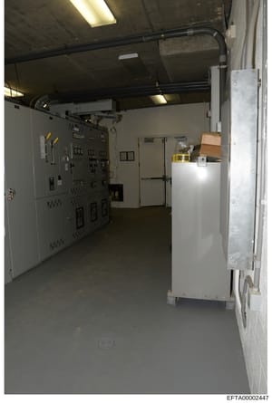 This is an evidence photograph showing the interior of an industrial or utility control room, featuring electrical panels, circuit breakers, piping infrastructure, and storage areas. The image appears to be documentation of a building's mechanical or