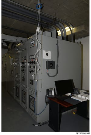 This photograph shows an industrial control panel system labeled with 'G' in what appears to be a facility equipment room or control center. The image captures electrical control panels with various switches, indicators, and control mechanisms, along