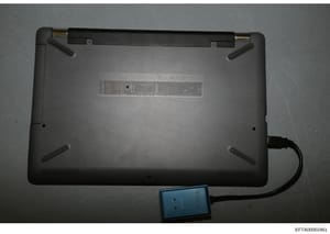 This is a photograph of the underside of a laptop computer, showing the bottom panel with ventilation grilles and what appears to be an external storage device or drive connected via cable. The image is marked as evidence (EFTA00002461) in the Jeffre