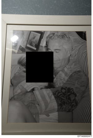 This is a black and white photograph that has been heavily redacted with a large black rectangle covering the central portion of the image. The visible portions show what appears to be an indoor domestic setting with framed artwork on walls and strip
