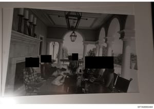 This black and white photograph shows the interior of an elegant, architecturally distinctive space featuring classical columns, arched doorways, and decorative lighting. Multiple individuals are present at what appears to be a dining table or gather