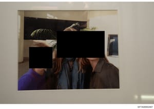 This is an evidence photograph showing an interior residential space with multiple people present. The faces of all individuals have been redacted with black rectangles, obscuring their identities. The image shows a doorway leading to a hallway or ad