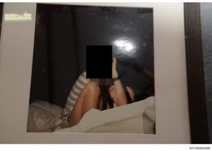 This is a photograph showing a person on a bed with their face obscured by a black redaction box. The image appears to be evidence documentation from the investigation, with the person's identity protected through redaction. The photograph shows inte