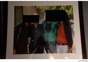 This is an evidence photograph showing three people standing outdoors on a street with trees and storefronts visible in the background. The faces of all three individuals have been redacted with black bars for privacy or investigative purposes. One p