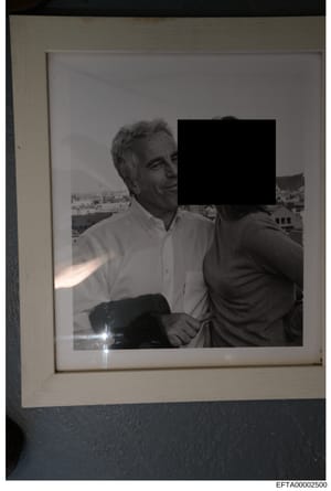 This is a black and white photograph showing two men at what appears to be a high-altitude location with a cityscape visible in the background. One man wears a white shirt and is clearly visible; the other man's face is redacted with a black rectangl