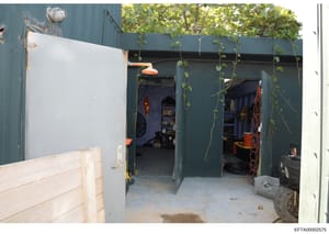 This is an evidence photograph showing the interior of a metal storage container or utility building. The space contains various equipment, tools, and supplies including orange-handled tools, coiled red rope or cable, shelving units, and electrical e