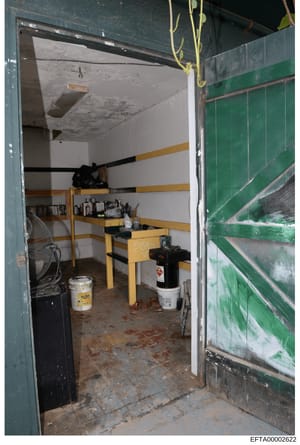 This photograph shows the interior of a storage or utility room, likely at one of Epstein's properties. The room contains shelving with various supplies and equipment, including fans, buckets, cleaning supplies, and other items. The space appears clu
