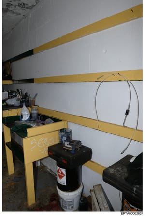 This is a photograph of an interior storage or utility room, likely from one of Epstein's properties, showing yellow metal shelving units with white walls and various stored items including containers, cables, and equipment. The space appears to be a