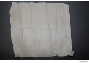 This is a photograph of what appears to be a blank, heavily creased, or deteriorated white cloth or paper document. The item shows significant wear with multiple fold marks and discoloration, suggesting it may be aged evidence material. The document'