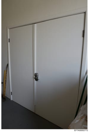 This is a photograph of a white sliding closet door with a digital keypad lock installed on the right panel. The image appears to be from an interior space and was taken as evidence documentation during the investigation. The presence of the security