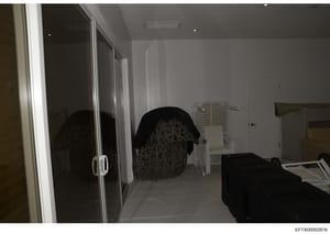 This is a photograph of an interior bedroom space, likely from one of Epstein's properties documented during the investigation. The image shows a modern room with sliding glass closet doors, white walls, recessed lighting, and various furniture and s