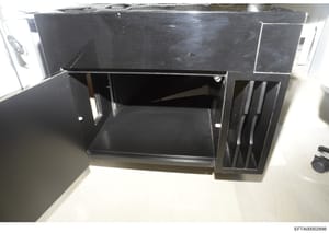 This is a photograph of a black desk with built-in storage features, including a hutch-style upper section and side filing or storage compartments. The image appears to be evidence documentation from a property search or seizure, likely taken during 