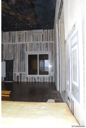 This is a photograph of an interior room showing striped wallpaper in muted tones, a dark ceiling, and what appears to be a window or glass door. The image is taken from a doorway looking into the room. The photograph appears to be evidence documenta
