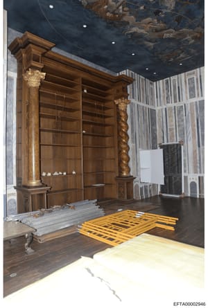 This is a photograph of an elegantly decorated interior room featuring custom wooden shelving units with ornamental columns, a painted ceiling, and various furnishings. The image appears to be documentation of a property's interior design, possibly f