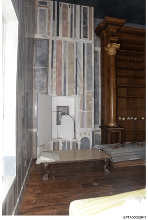 This photograph depicts an interior bedroom space, likely from one of Jeffrey Epstein's properties. The room features ornate wooden furniture including a carved wooden column with a Corinthian capital, striped wallpaper in muted tones, hardwood floor