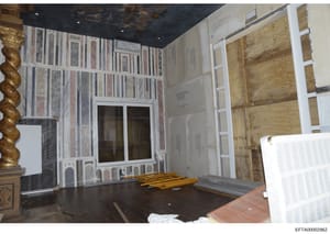 This photograph documents an interior room under renovation, showing extensive wall and ceiling work with exposed framing, material samples, construction equipment, and temporary protective covering. The image appears to be evidence documentation fro