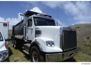 This is a photograph of a white commercial dump truck with a black dump bed, equipped with a roof-mounted light bar. The image appears to be documentation of equipment or property, possibly related to construction, maintenance, or property management