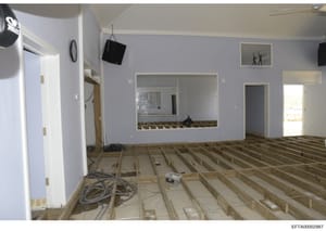 This photograph shows an interior room under construction or renovation, featuring lavender-painted walls, exposed wooden floor joists, and framed openings with mirrors. The space appears to be a residential interior, likely from one of Epstein's pro