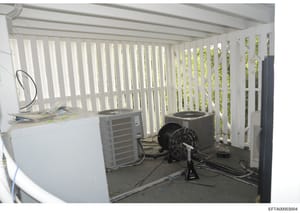 This photograph shows an interior equipment or utility room containing multiple HVAC units, air conditioning systems, and ventilation equipment. The room features white vertical blinds or louvers, concrete flooring, and various mechanical systems in 