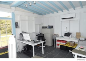 This photograph documents an office or workspace interior, featuring contemporary furniture, computer equipment, filing systems, and storage. The space appears to be part of a property documented in the Epstein investigation files, showing a well-org