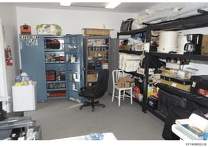 This is a photograph of an organized storage or maintenance room, likely from one of Jeffrey Epstein's properties. The space contains multiple storage cabinets, shelving units, tools, cleaning supplies, and household items. The room appears to be a u