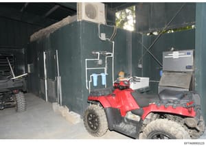 This photograph documents the interior of a utility storage structure containing recreational vehicles (ATVs), water filtration systems, HVAC equipment, and various storage items. The image appears to be evidence documentation from a property search 