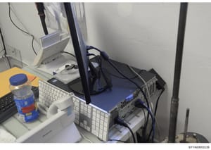 This is a photograph of a computer workstation setup featuring multiple monitors, keyboards, and server equipment with network cables. The image shows IT infrastructure that may have been used for data storage, communications, or business operations 