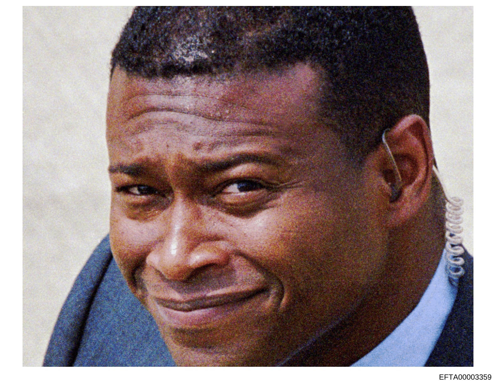 This is a color photograph of an unidentified male subject, appearing to be a headshot or portrait taken as part of the investigation documentation. The image shows a close-up of the person's face and upper shoulders against a light background. The p