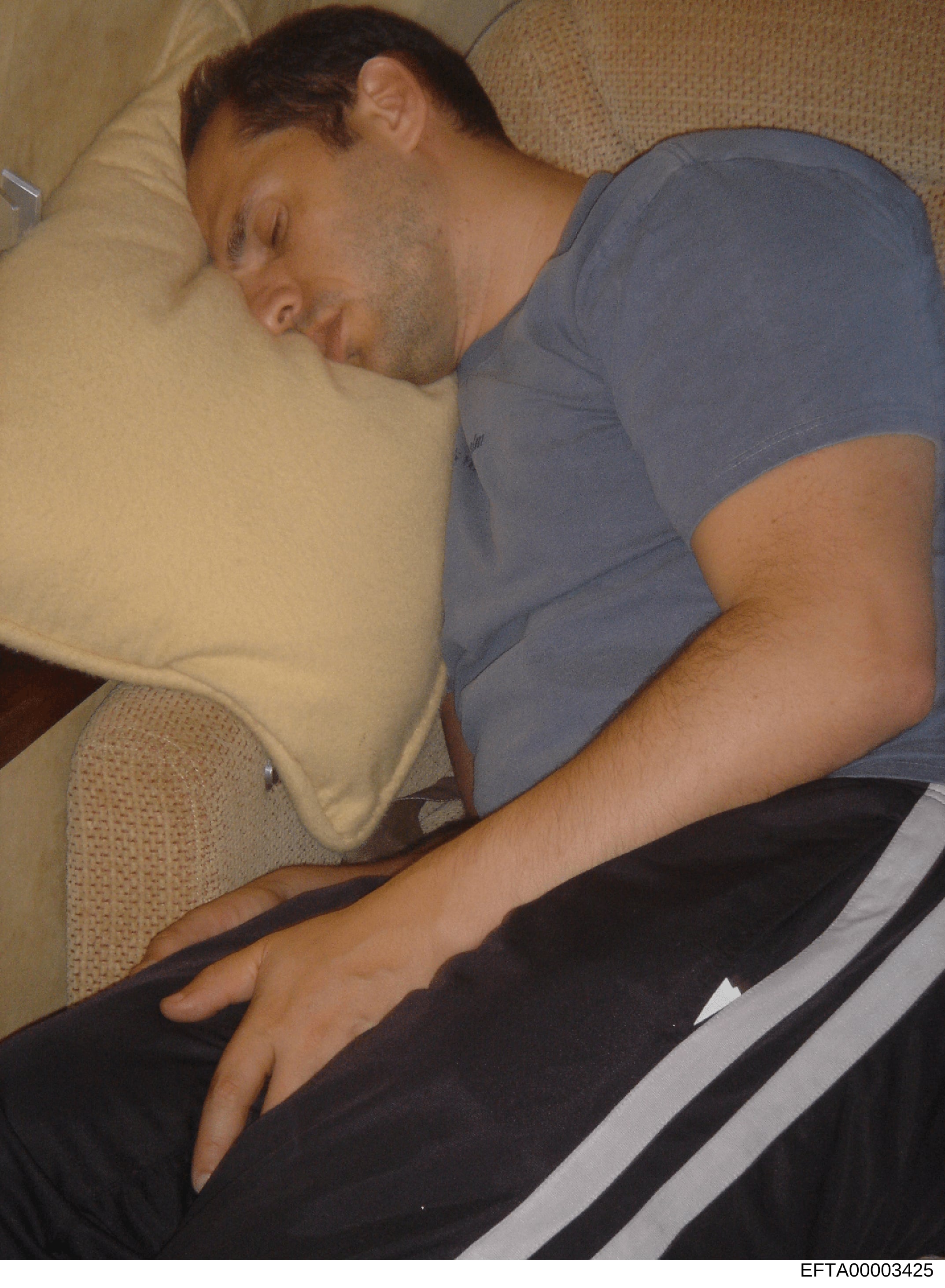 This is a personal photograph showing an adult male sleeping on a couch. The image appears to be casual domestic photography. Without additional context or identifying information visible in the image, the subject's identity and relevance to the inve