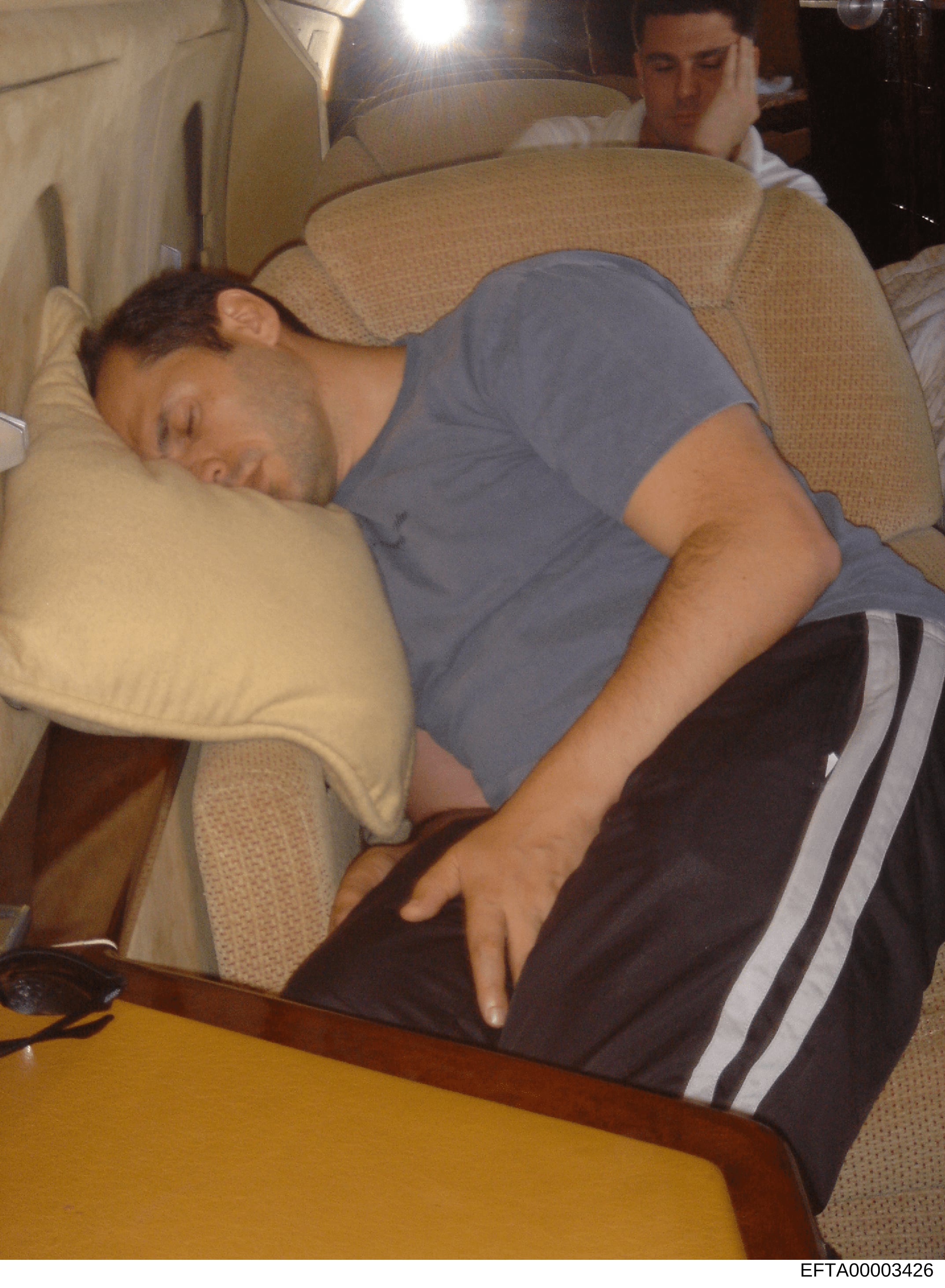 This is a photograph showing an individual resting on upholstered furniture, appearing to be in a casual indoor setting. The image was recovered as part of the Jeffrey Epstein investigation files. The photograph's relevance to the investigation is un